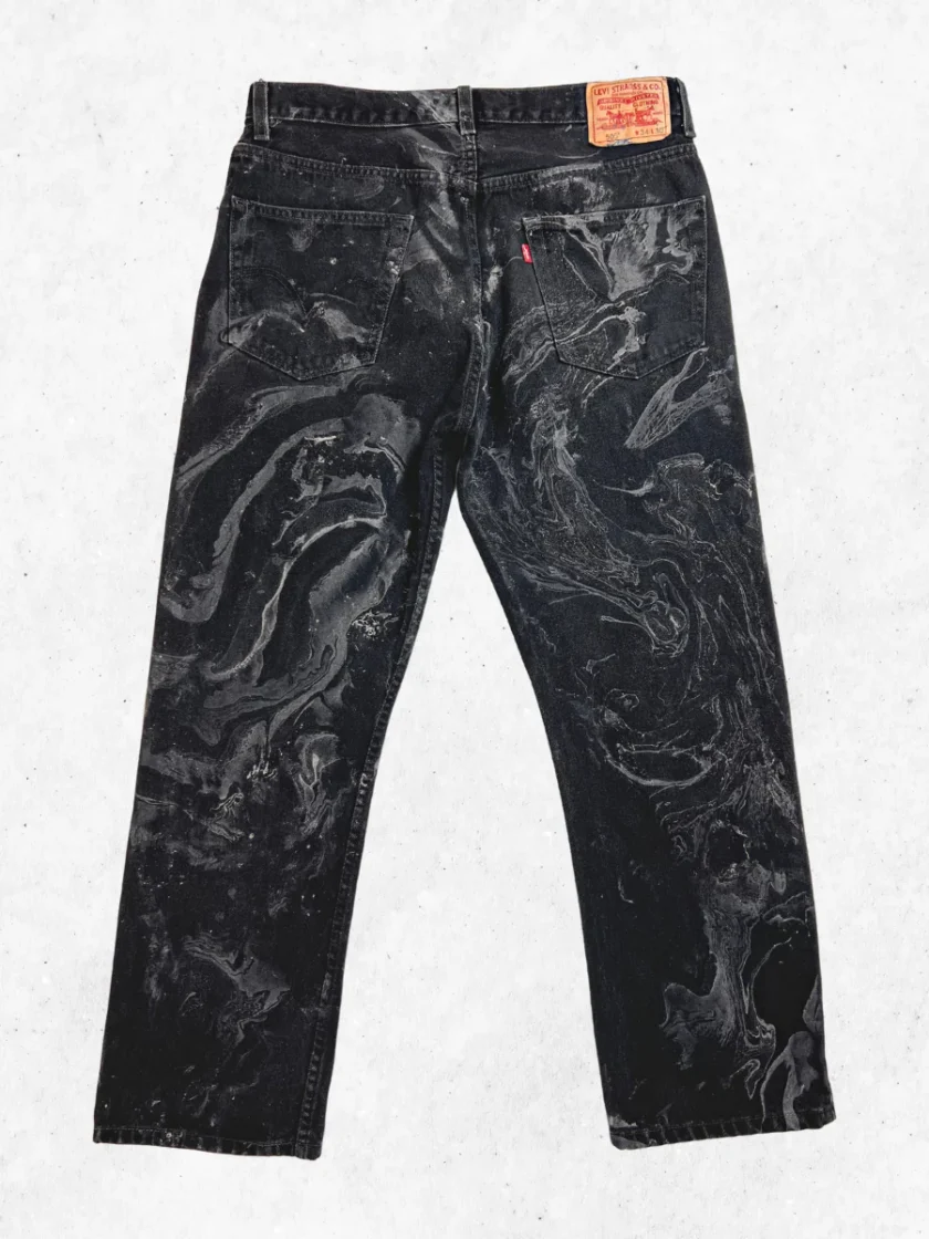 A pair of black jeans with black paint on them.