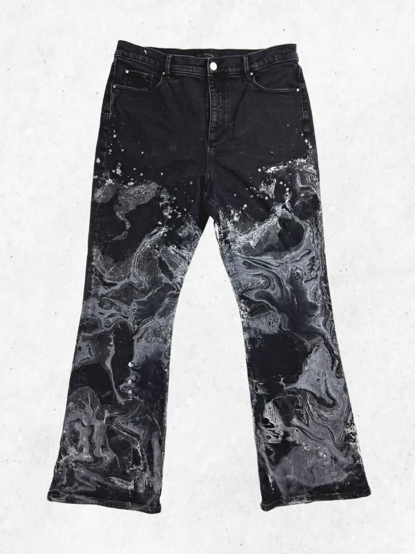 A pair of black jeans with white paint on them.