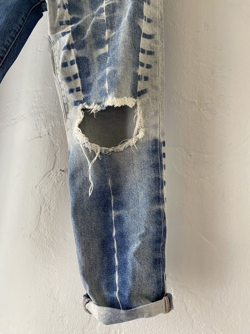 Close up of distressed and bleached blue jeans hanging on a clothes line.