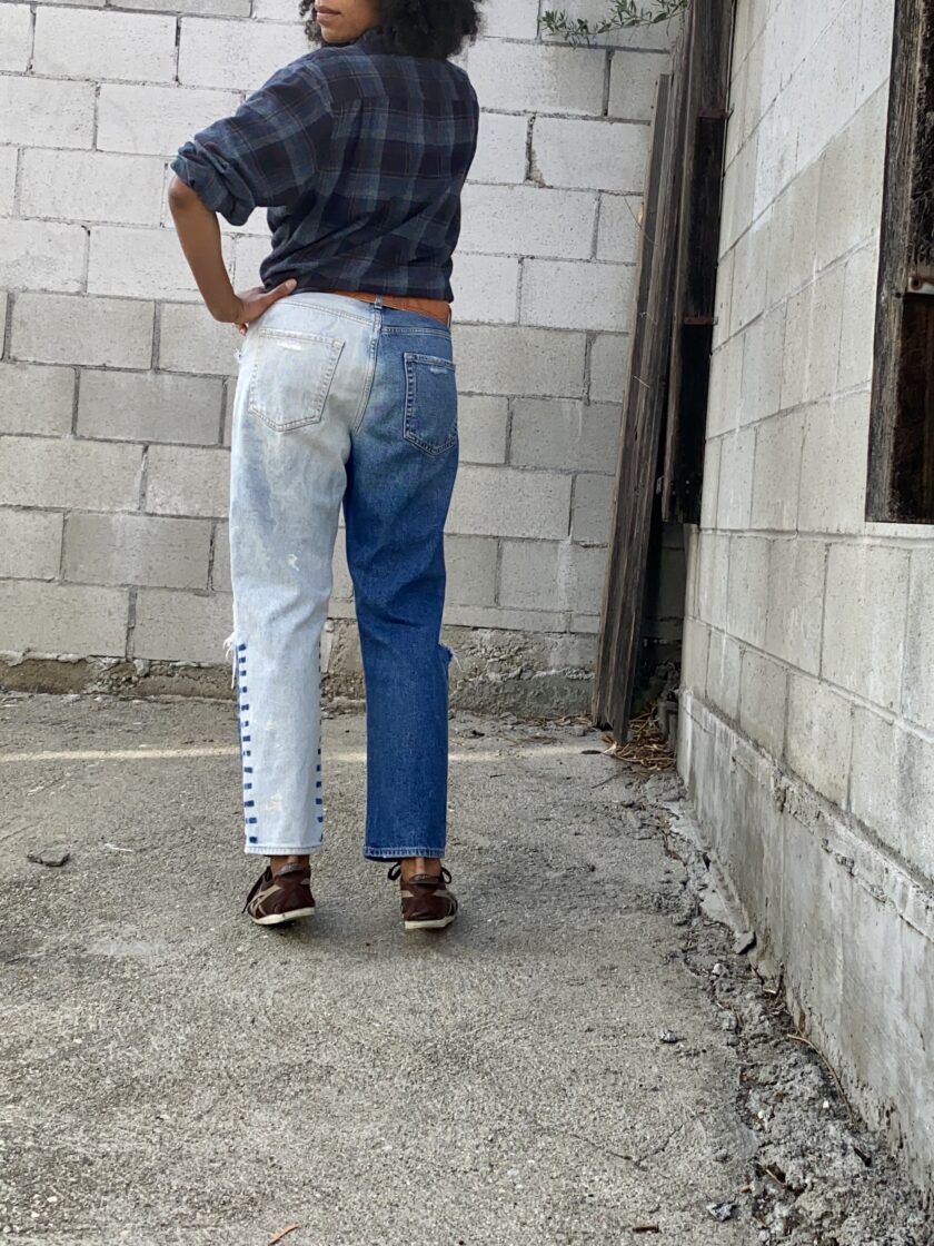 Back side of model wearing distressed blue jeans.