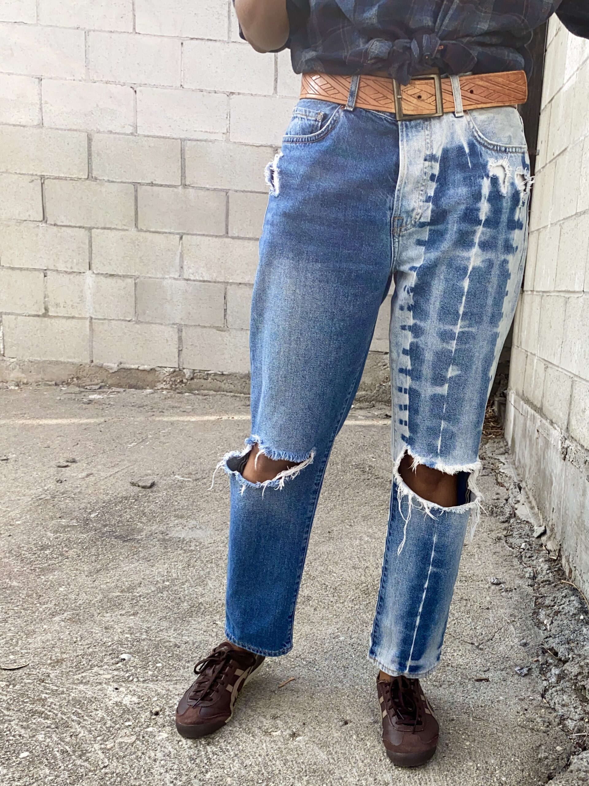 Front side of model wearing distressed blue jeans.