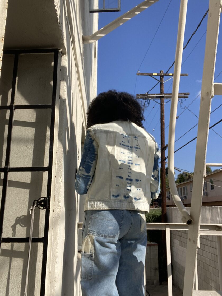 A woman wearing a denim jacket standing on a ladder.