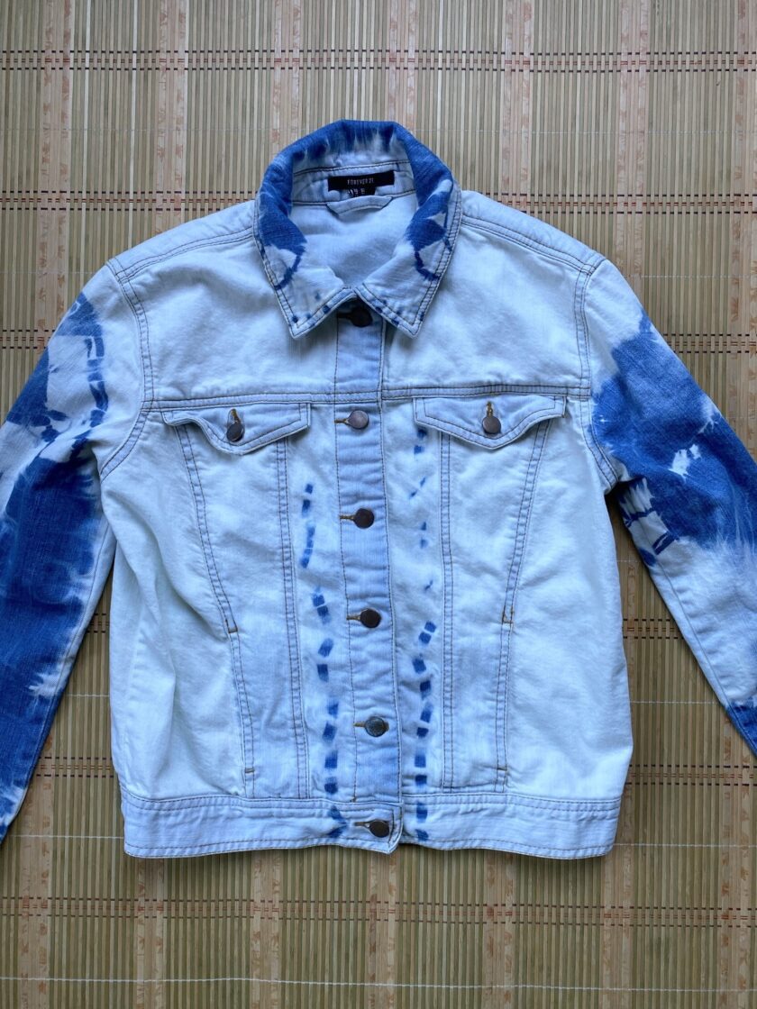 A blue and white tie dyed denim jacket on a bamboo mat.