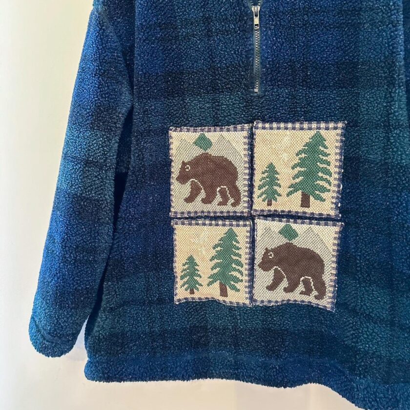 A blue jacket with bears and trees on it.