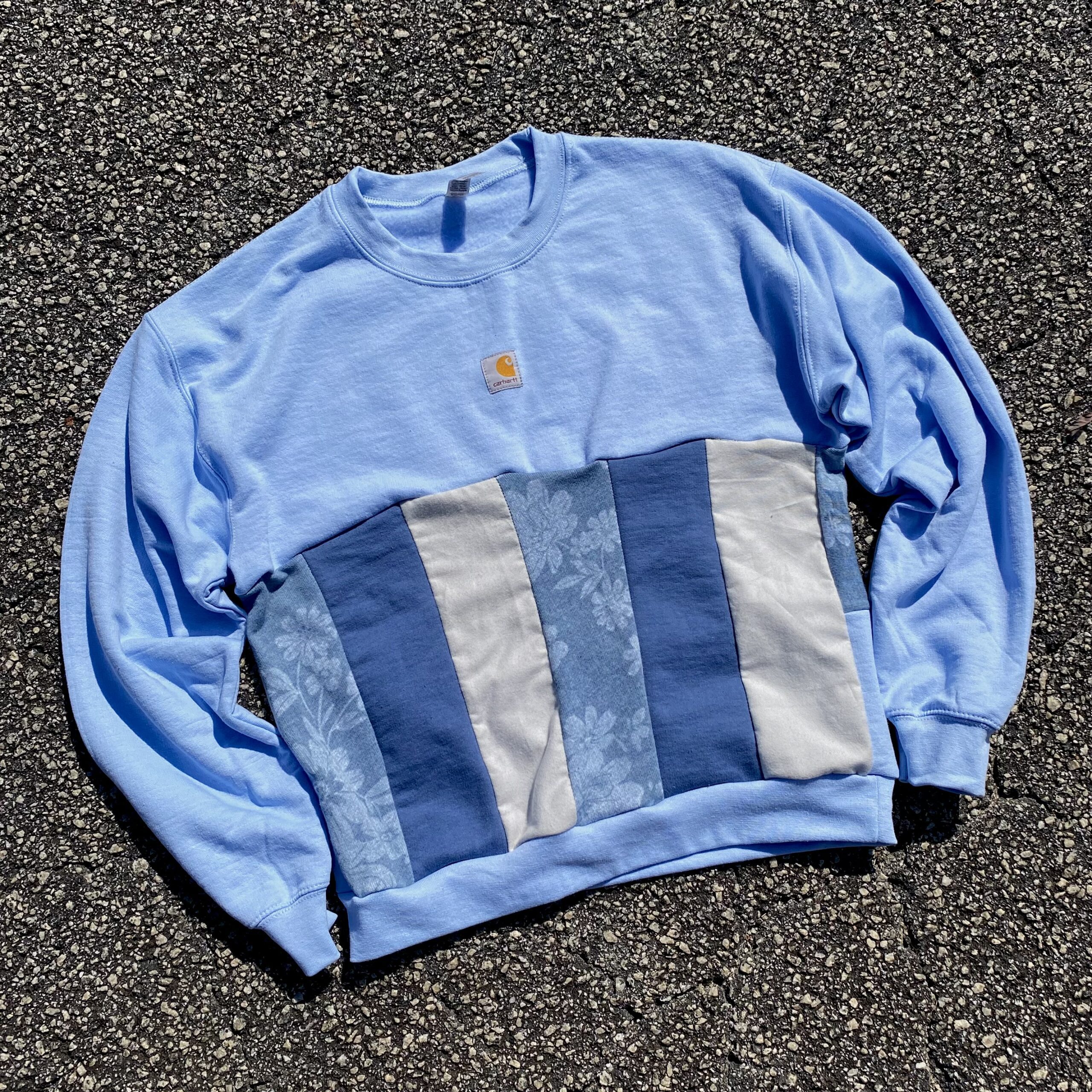 A blue and grey sweatshirt laying on the ground.