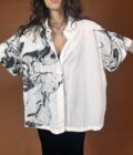 A woman wearing a white shirt with black and white marble print.