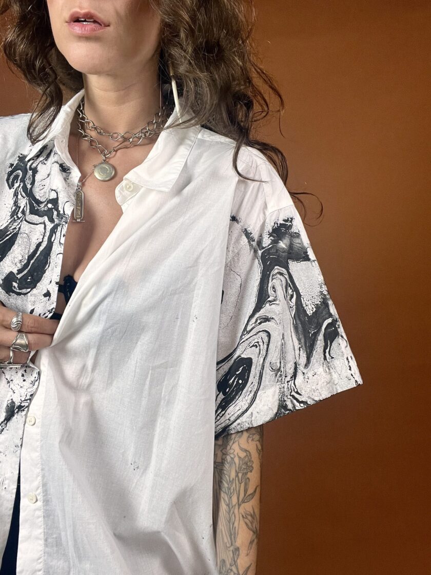 A woman in a white shirt with black and white tattoos.