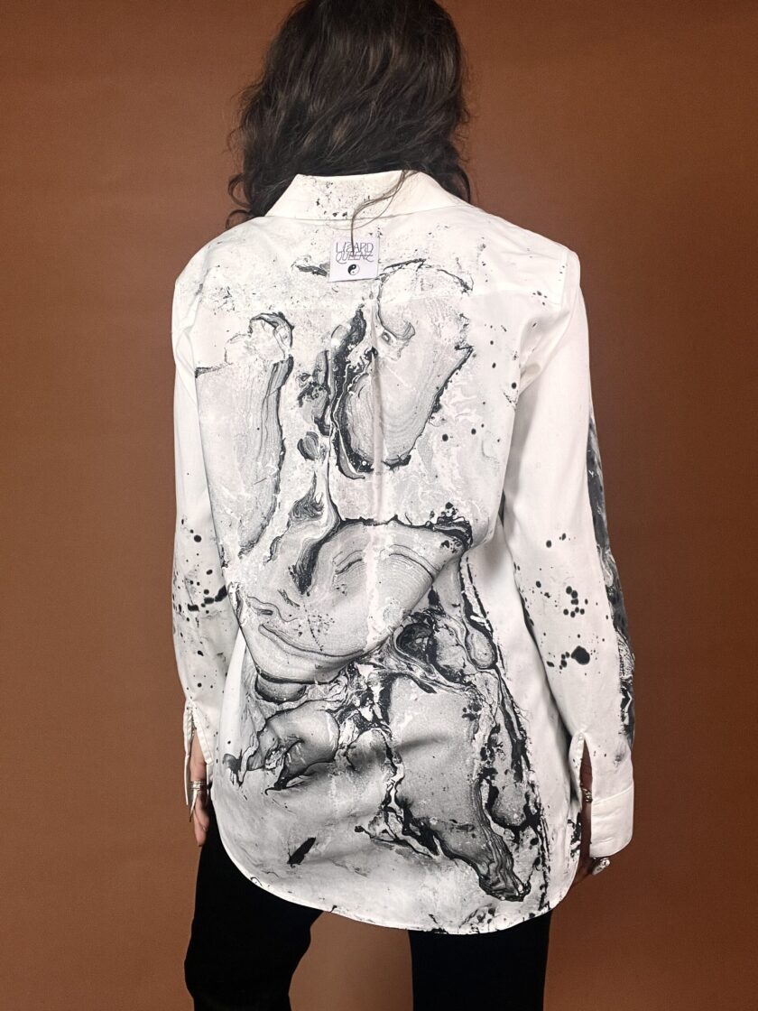 The back of a woman wearing a white shirt with black paint on it.