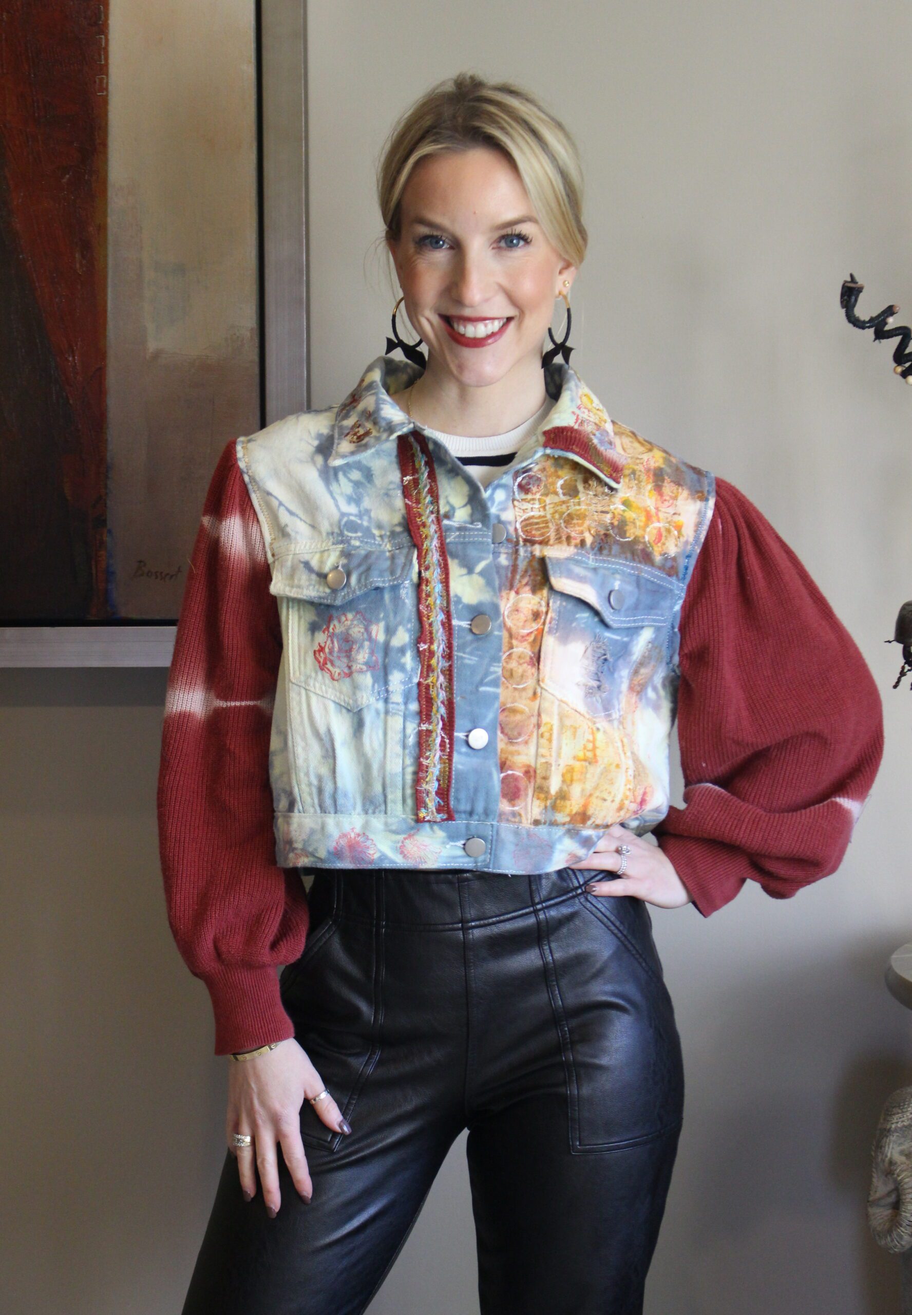 A woman wearing a denim jacket and leather pants.