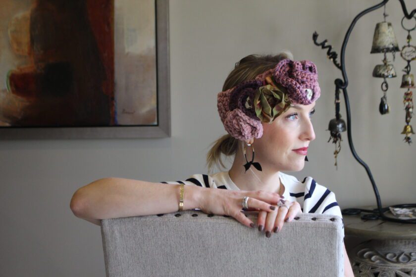 A woman sitting on a chair wearing a crocheted headband.