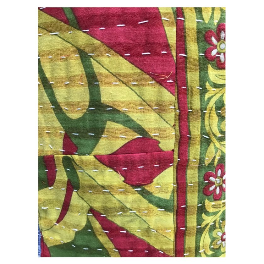 A red, yellow and green quilt with floral designs.