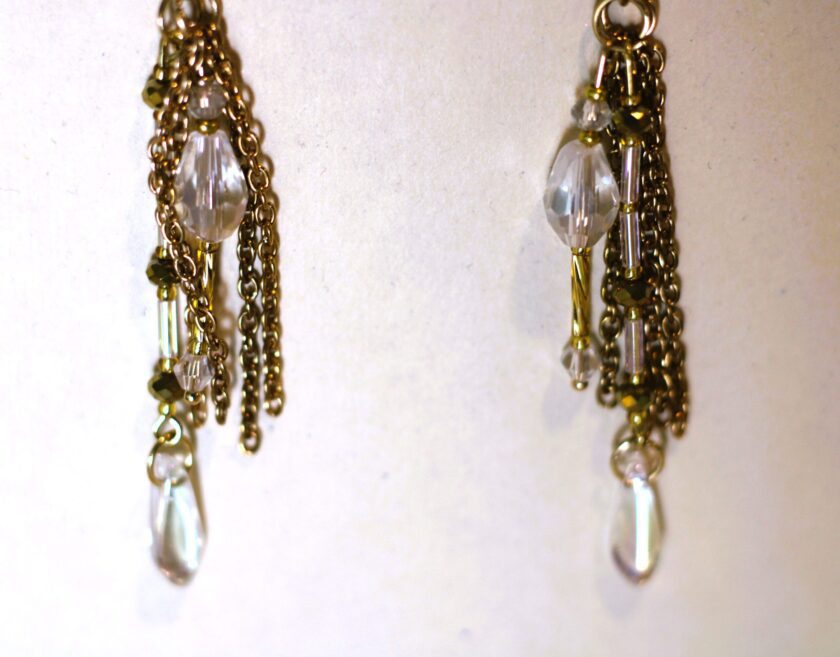 A pair of gold dangling earrings with clear crystals.
