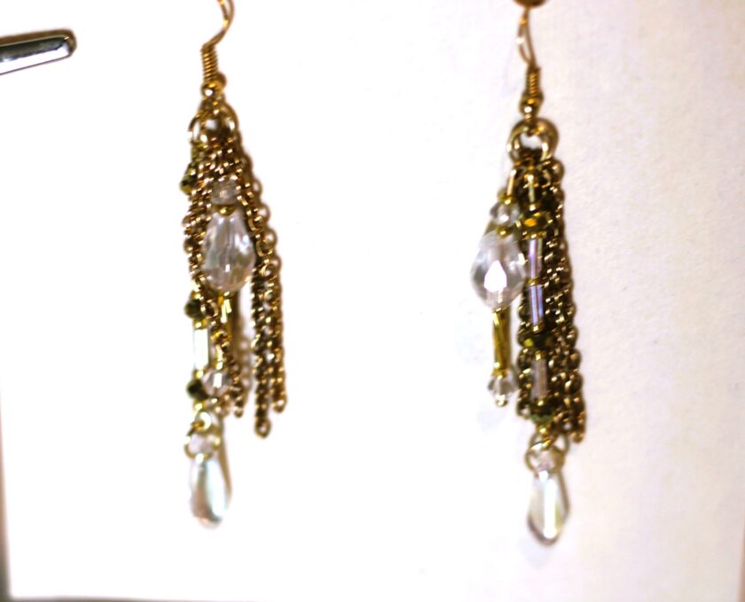 A pair of gold dangling earrings with clear crystals.