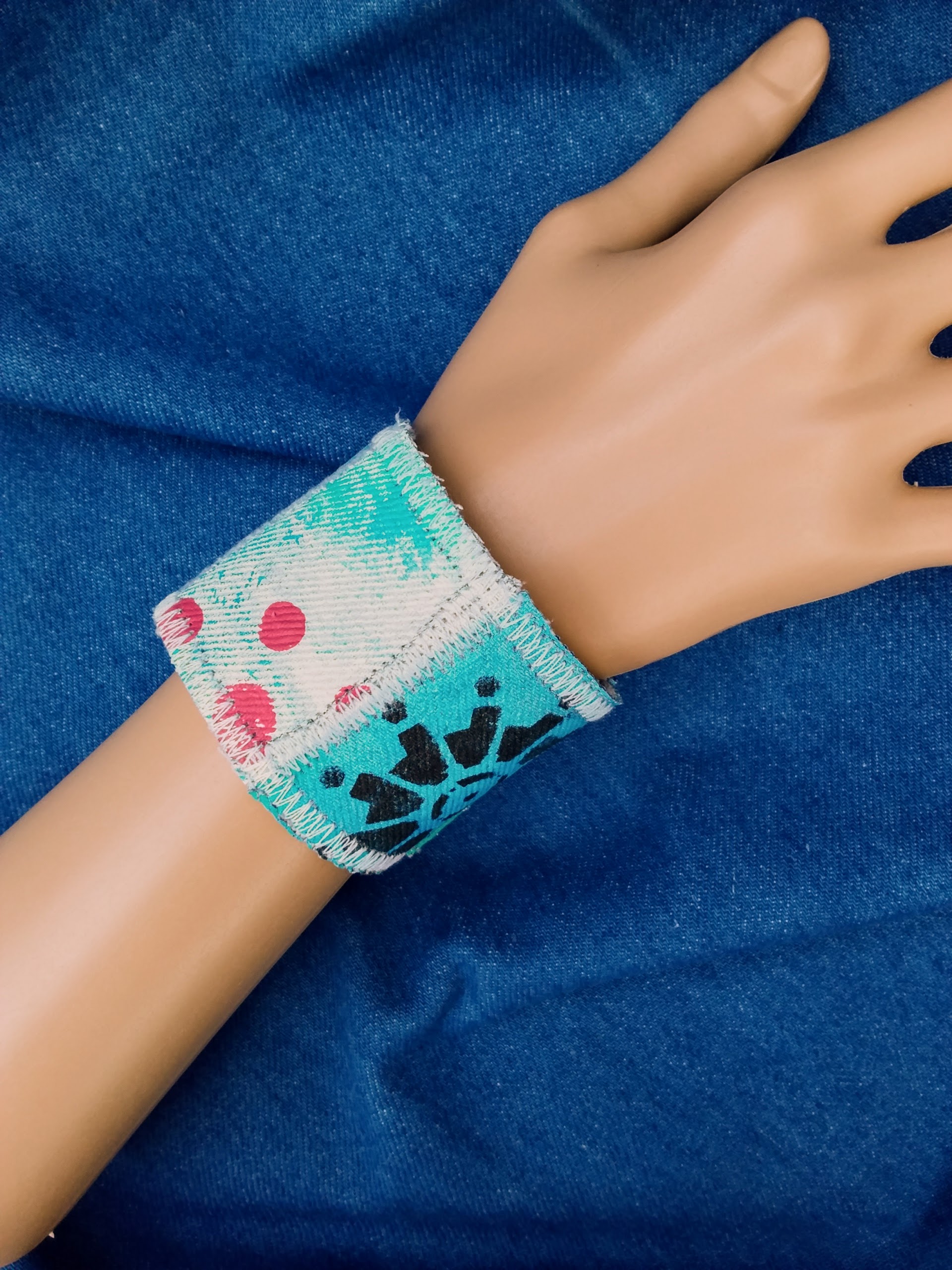 A recycled denim cuff bracelet with hand painted design
