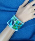 A hand painted recycled denim cuff bracelet in blue and green