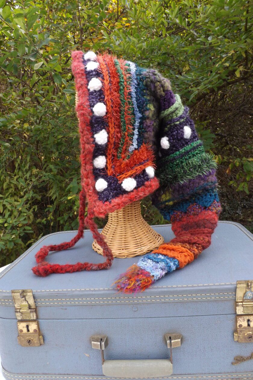 A colorful knitted hat on top of a suitcase.