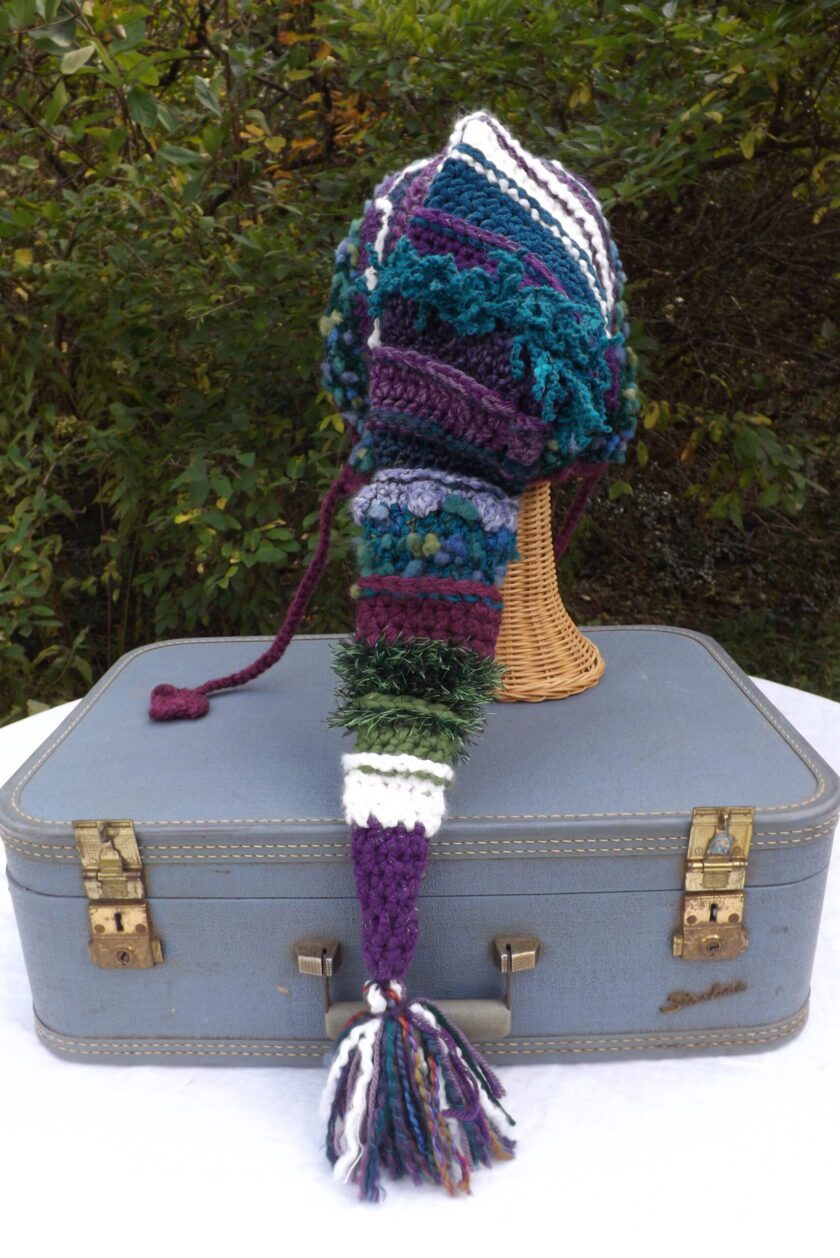 A crocheted hat is sitting on top of a suitcase.