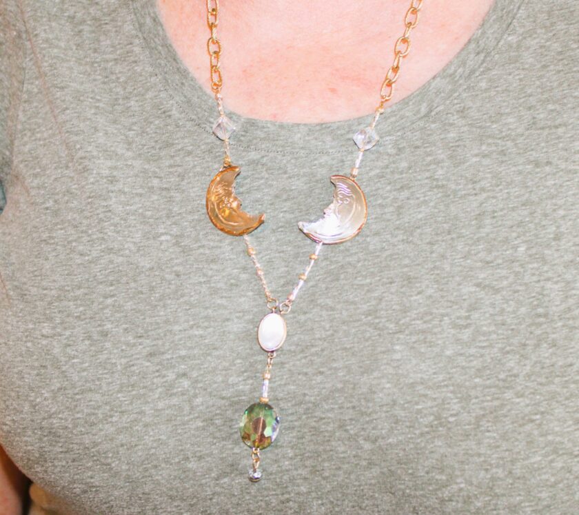 A woman wearing a necklace with a moon and moonstones.