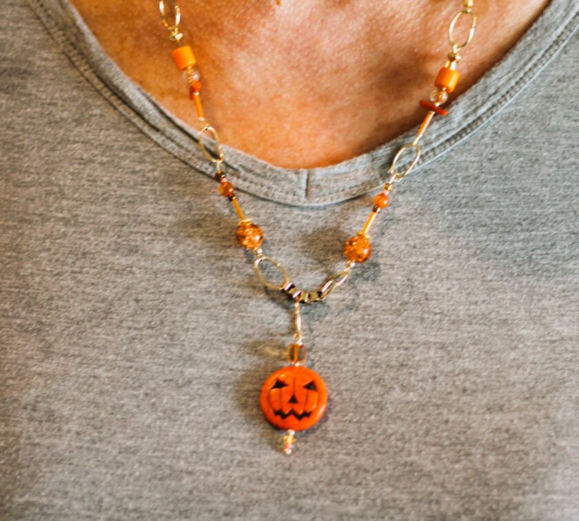 A woman wearing a necklace with a jack o lantern on it.