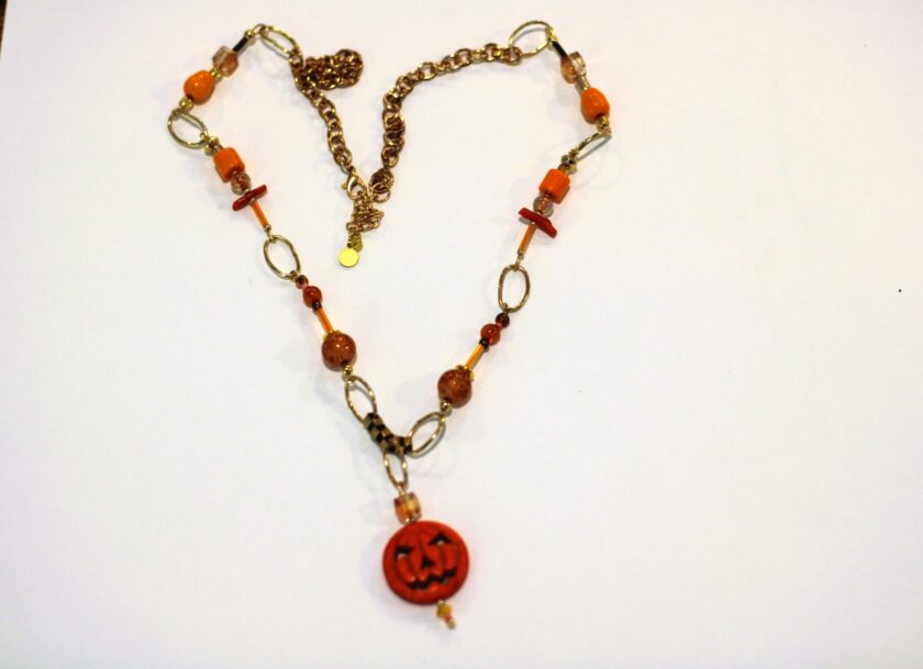 A necklace with an orange jack o lantern on it.
