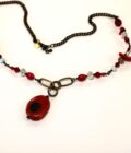 A necklace with red beads and a black chain.