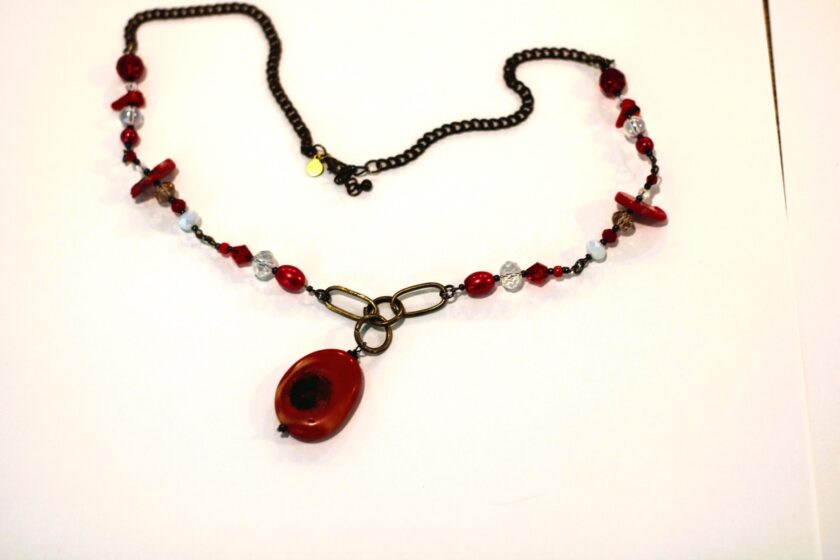 A necklace with red beads and a black chain.
