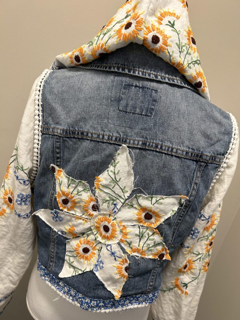 A denim jacket with sunflowers on it.
