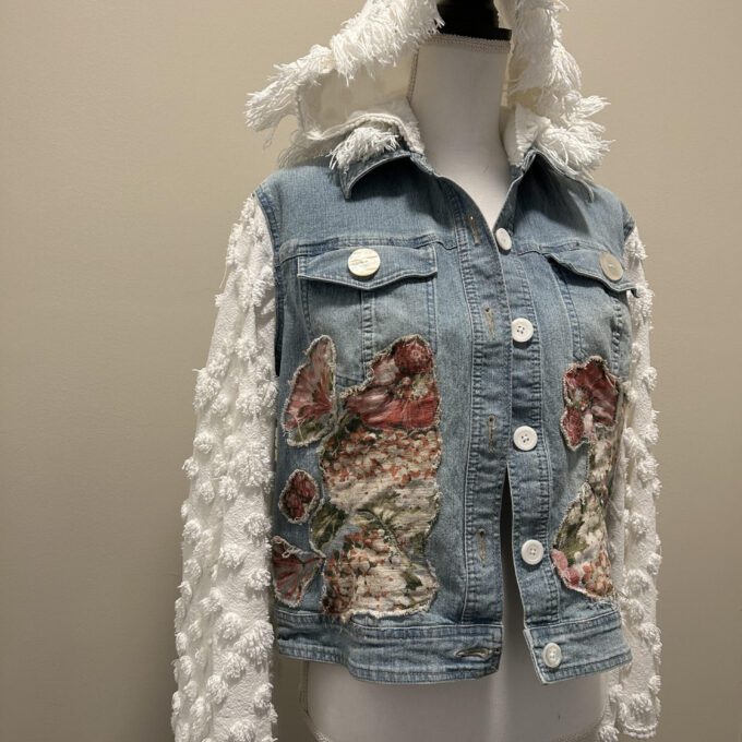 A denim jacket with a hood and flowers on it.