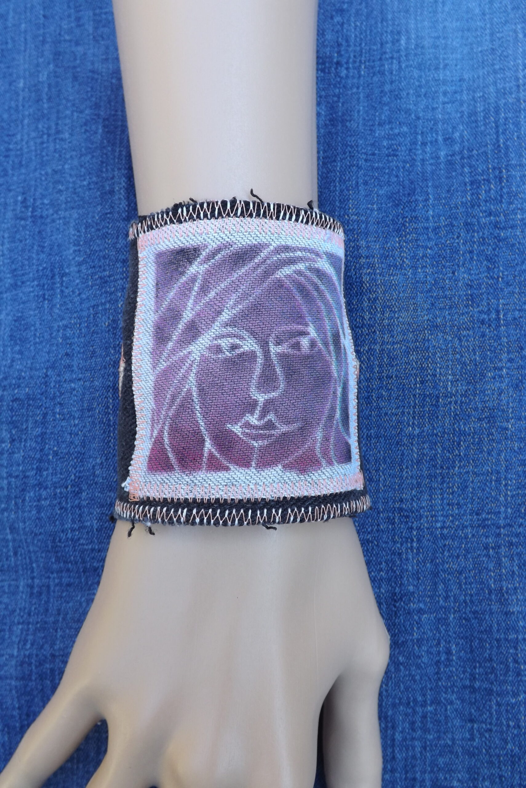 A woman's face adorns an upcycled denim cuff bracelet.