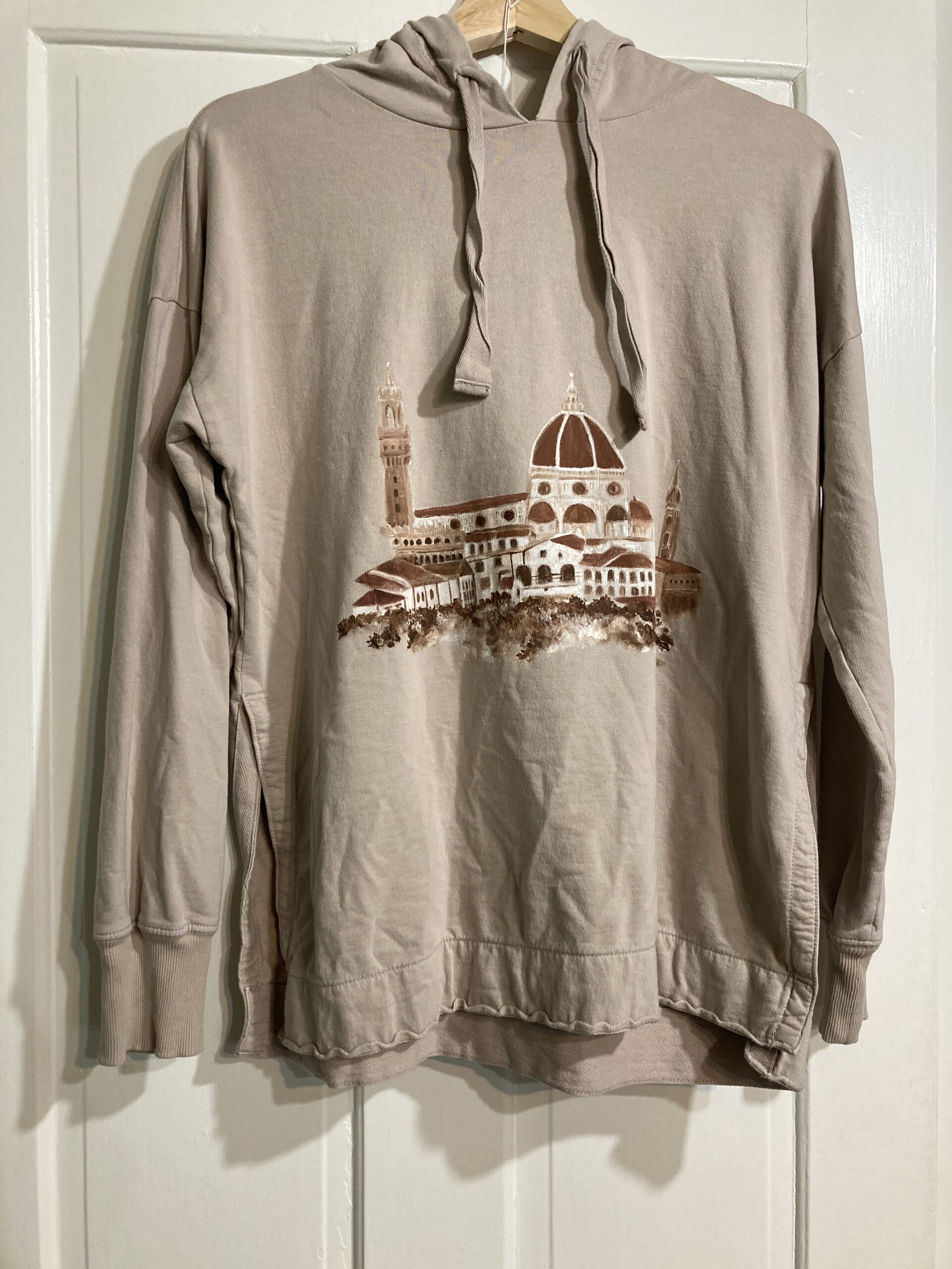 A beige hoodie hand-painted with a view of Florence