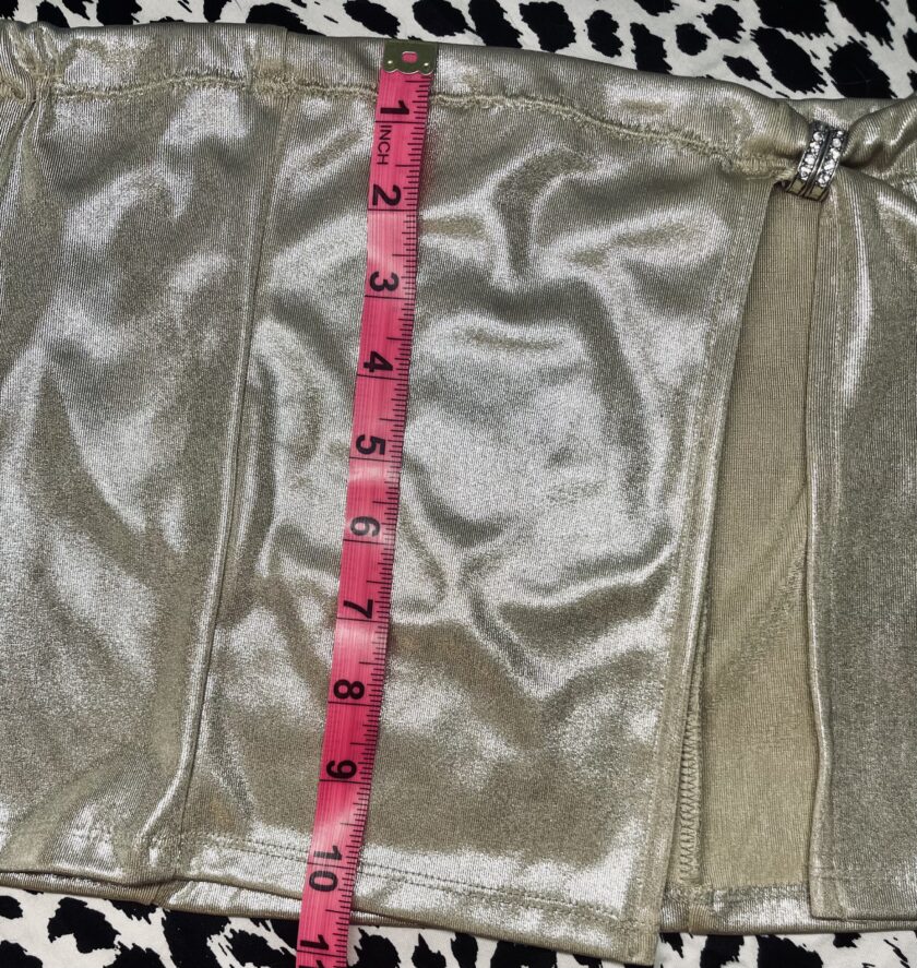 A measuring tape is used to measure the waist of a metallic skirt.