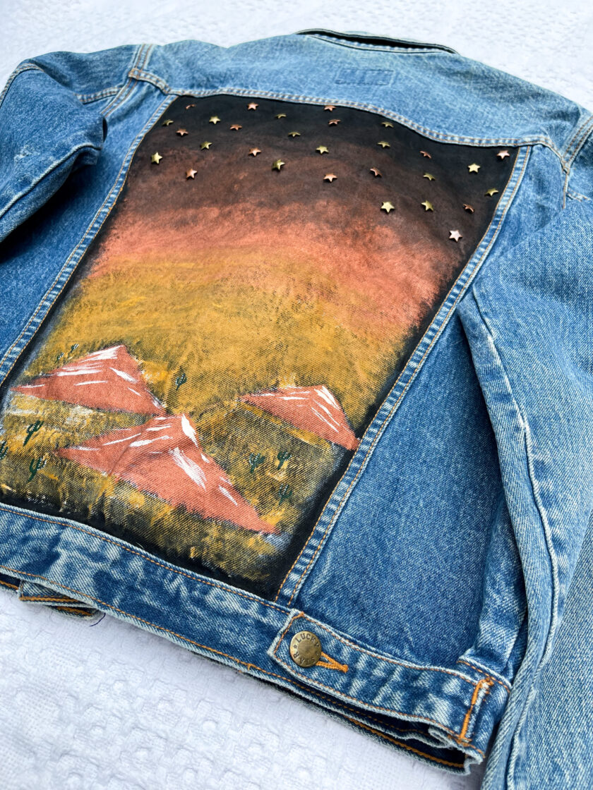 A denim jacket with a painting on it.