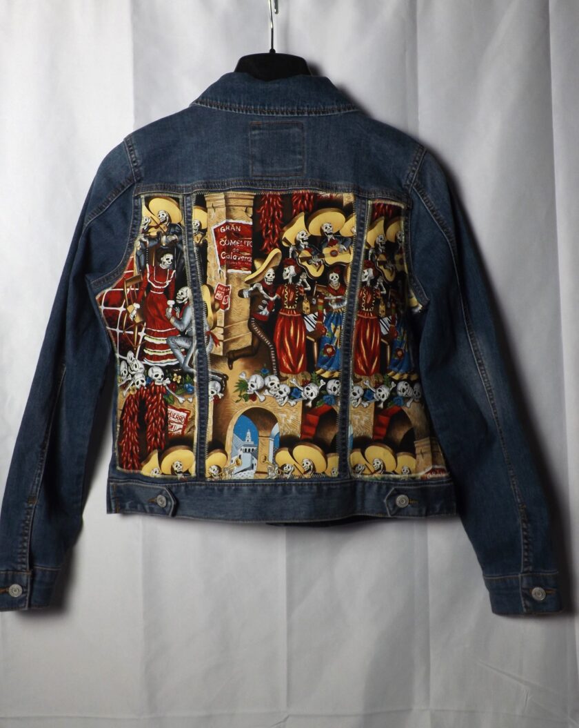 An upcycled denim jacket with calavera skeletons on it