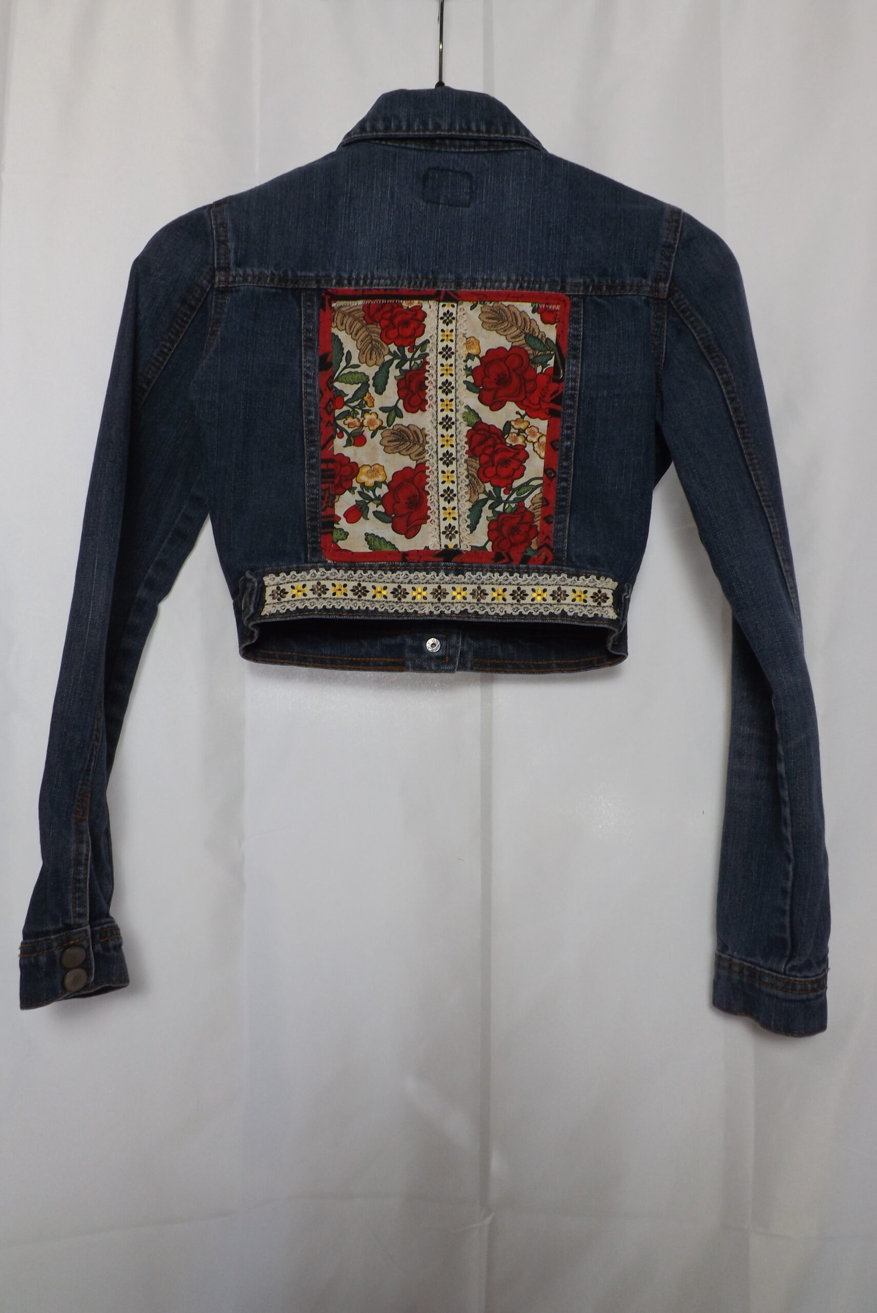 A cropped denim jacket with roses and embroidered lace