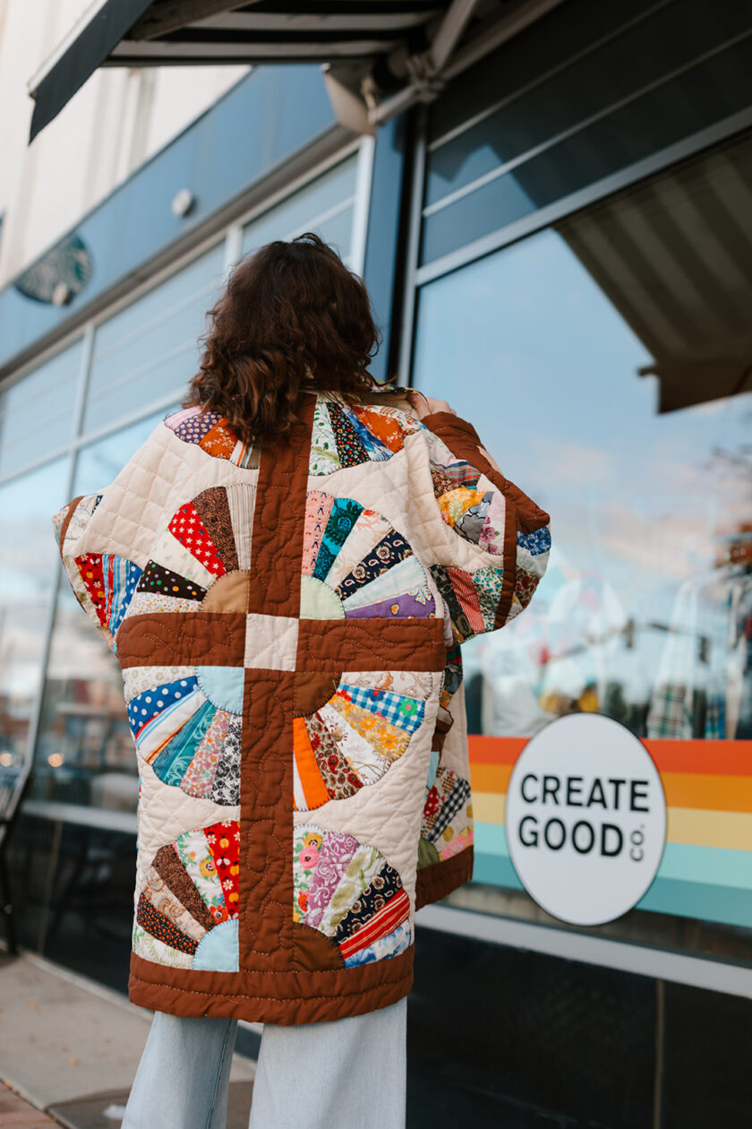 A woman wearing a quilted jacket in front of a store.