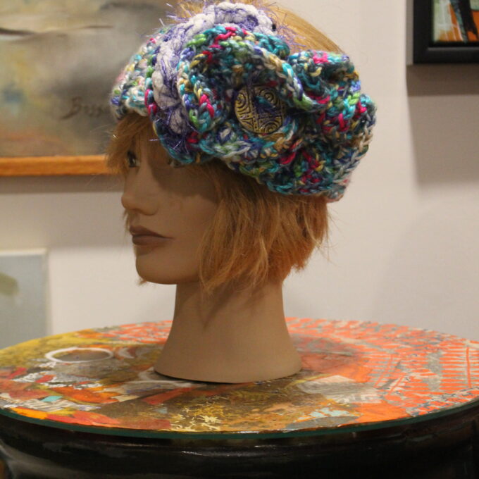 A mannequin head with a crocheted flower hat.