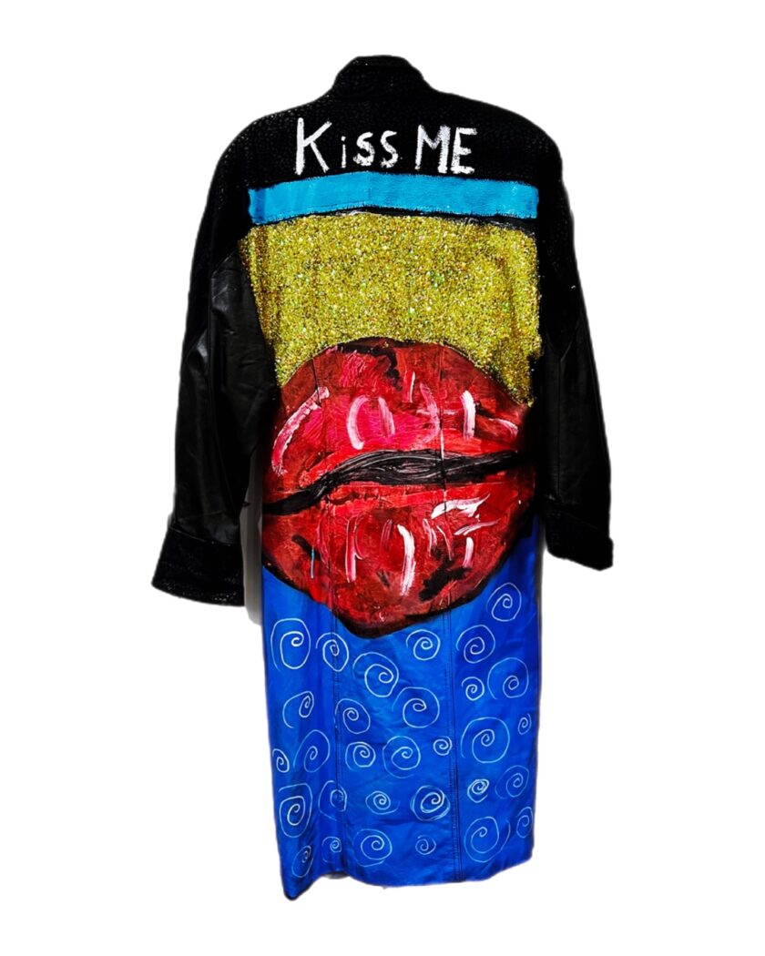 A black leather jacket with a kiss me painted on it.