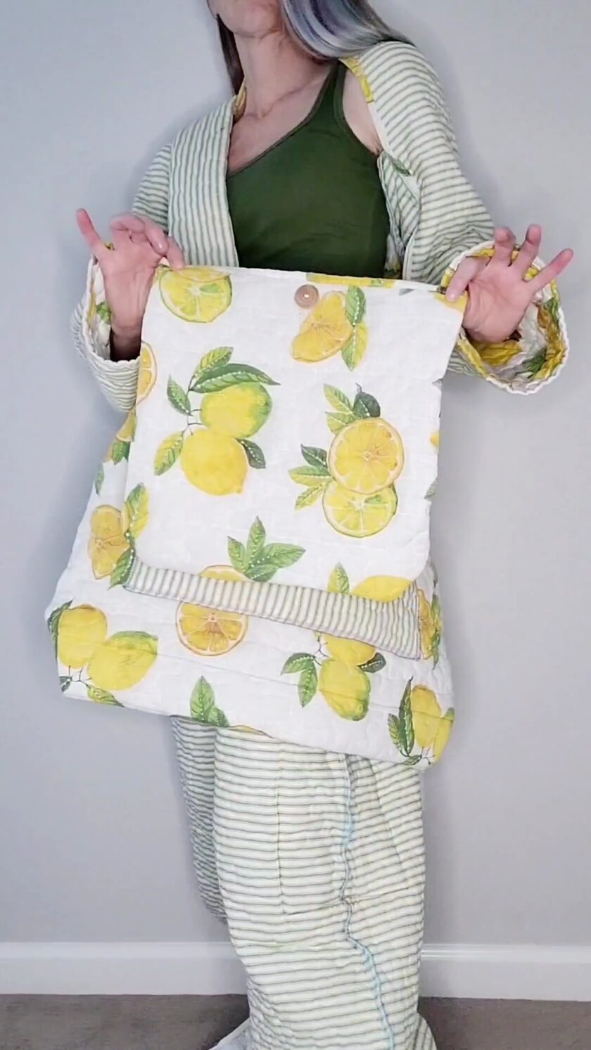 A woman holding a bag with lemons on it.