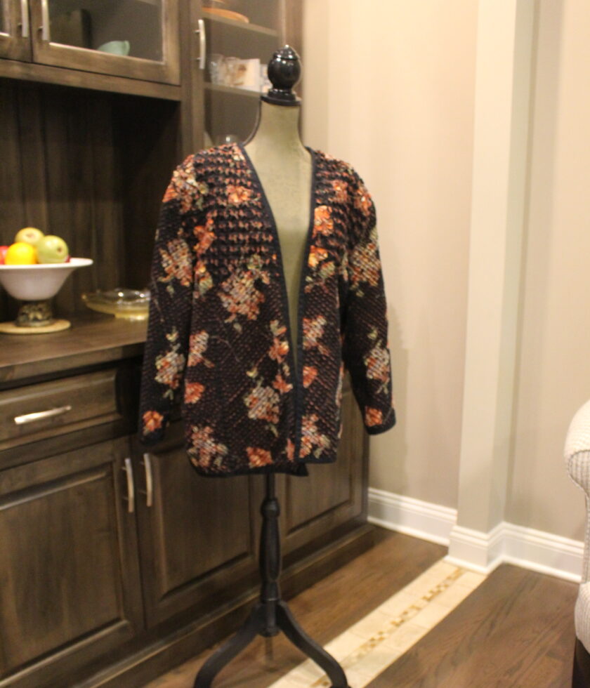 A mannequin in a living room with a floral jacket.