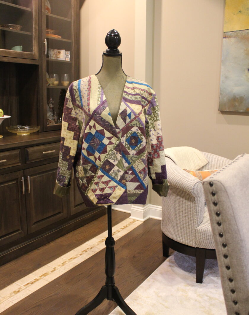 A mannequin wearing a colorful jacket in a living room.