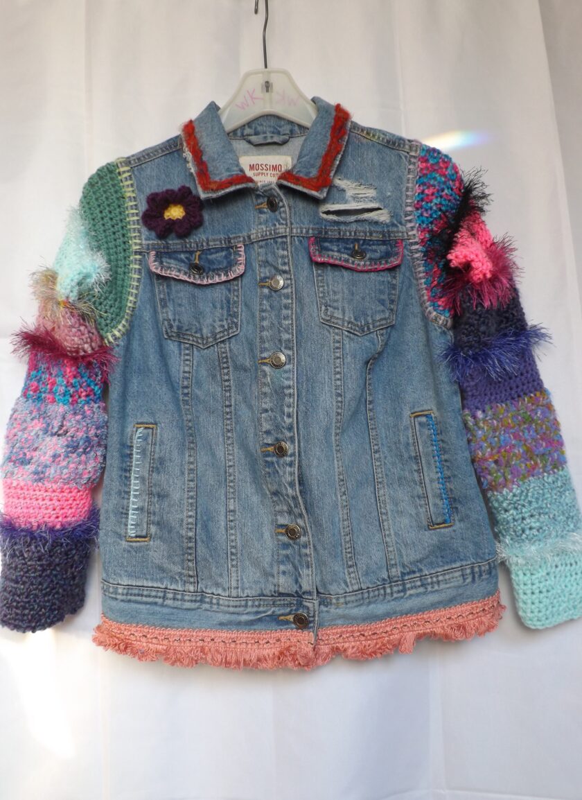 A denim jacket with colorful crochet sleeves.