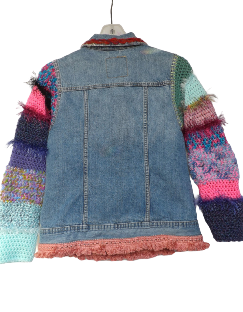 A denim jacket with colorful crochet sleeves and fringe trim.