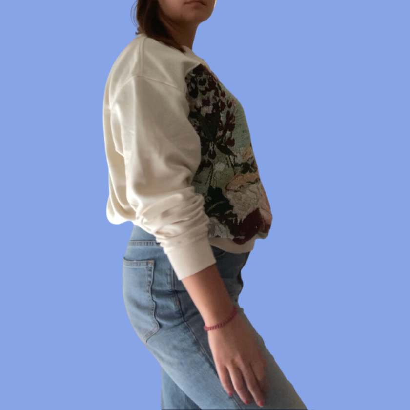 A woman wearing jeans and a sweatshirt standing on a blue background.