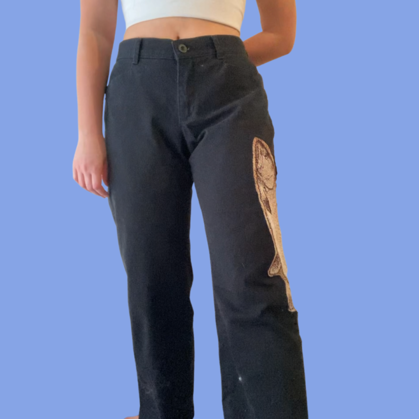A woman wearing a pair of black pants with a fish on them.