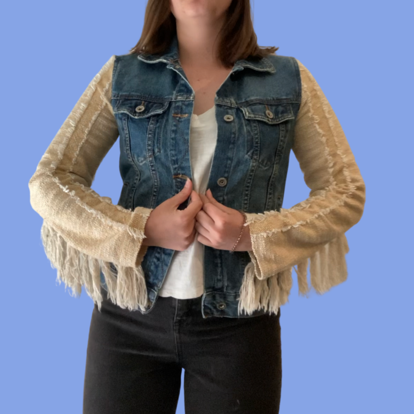 A woman wearing a denim jacket with fringe sleeves.