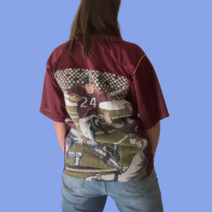 The back of a woman wearing a shirt with a football on it.