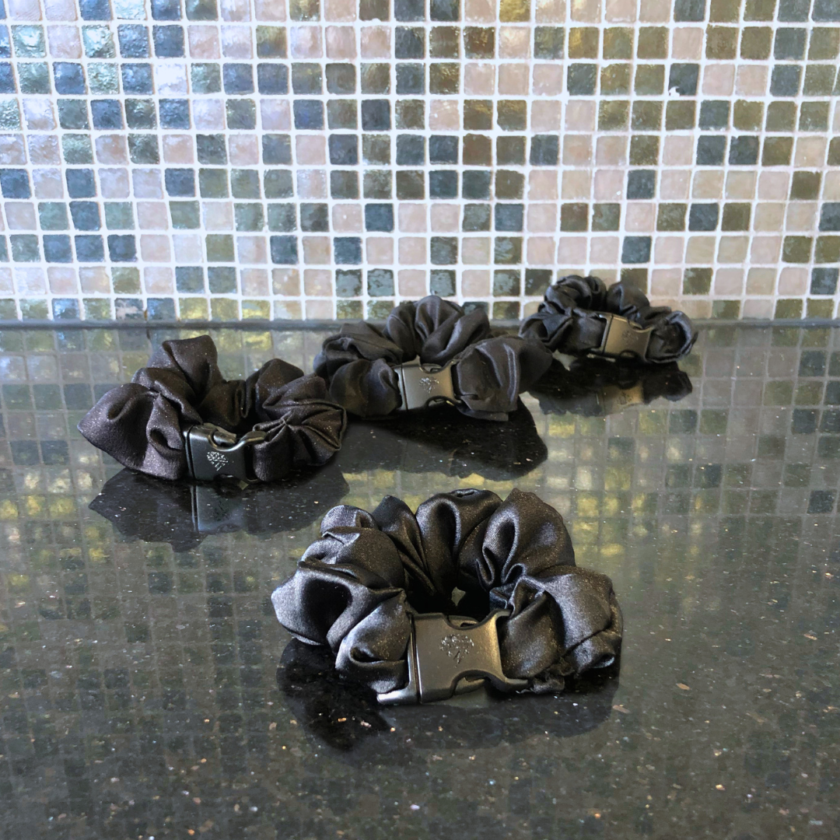 Three black Original Buckle Scrunchies on a counter top.