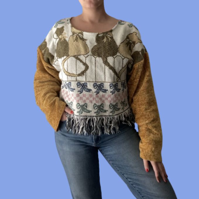 A woman wearing jeans and a sweater with fringes.
