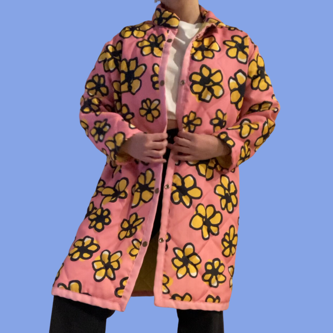 A woman wearing a pink coat with yellow flowers on it.