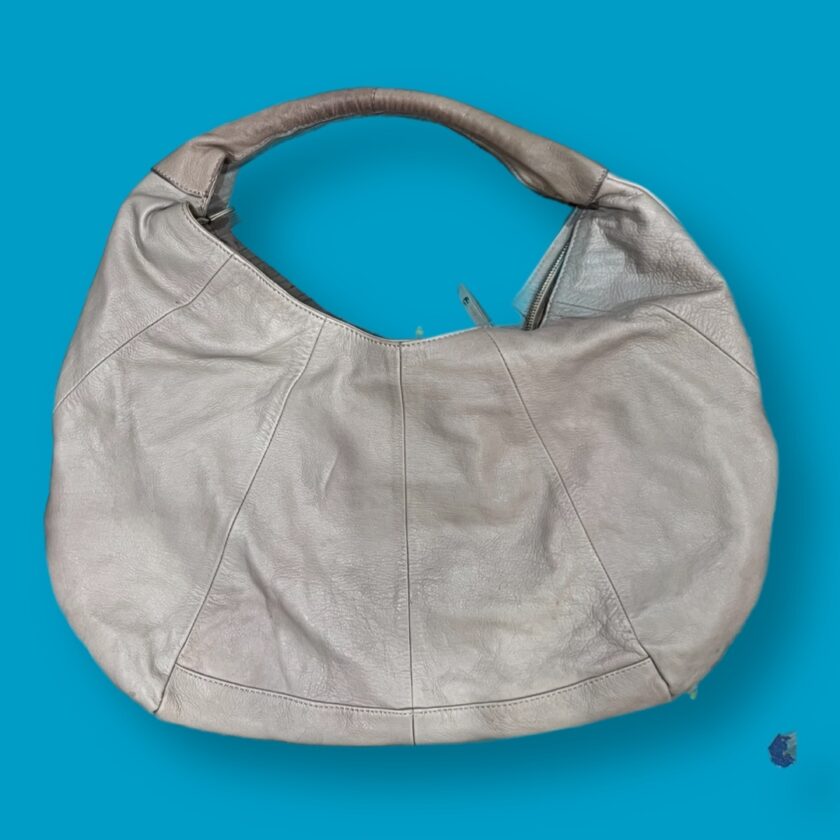 A grey leather hobo bag on a blue background.